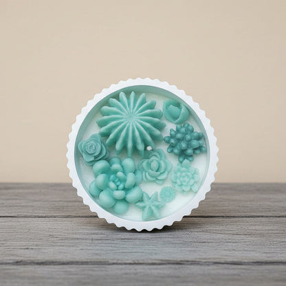 Round silicone mold with green floral and succulent designs on a wooden surface.